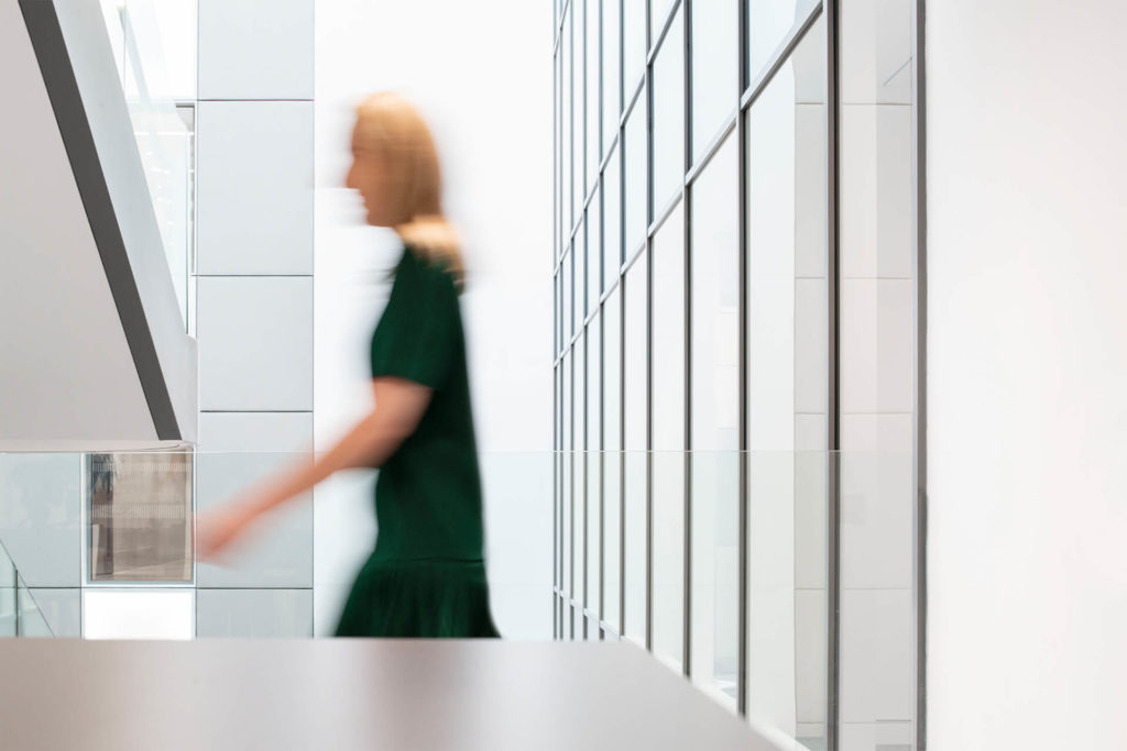 This photograph shows a person in in an office environment. The person is blurred to suggest motion. The person could be a member of the Fintech team.